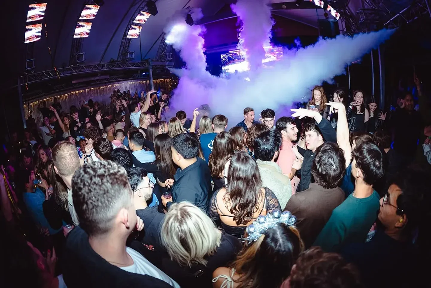 Energetic crowd at Summit nightclub in Austin, with smoke and vibrant atmosphere.