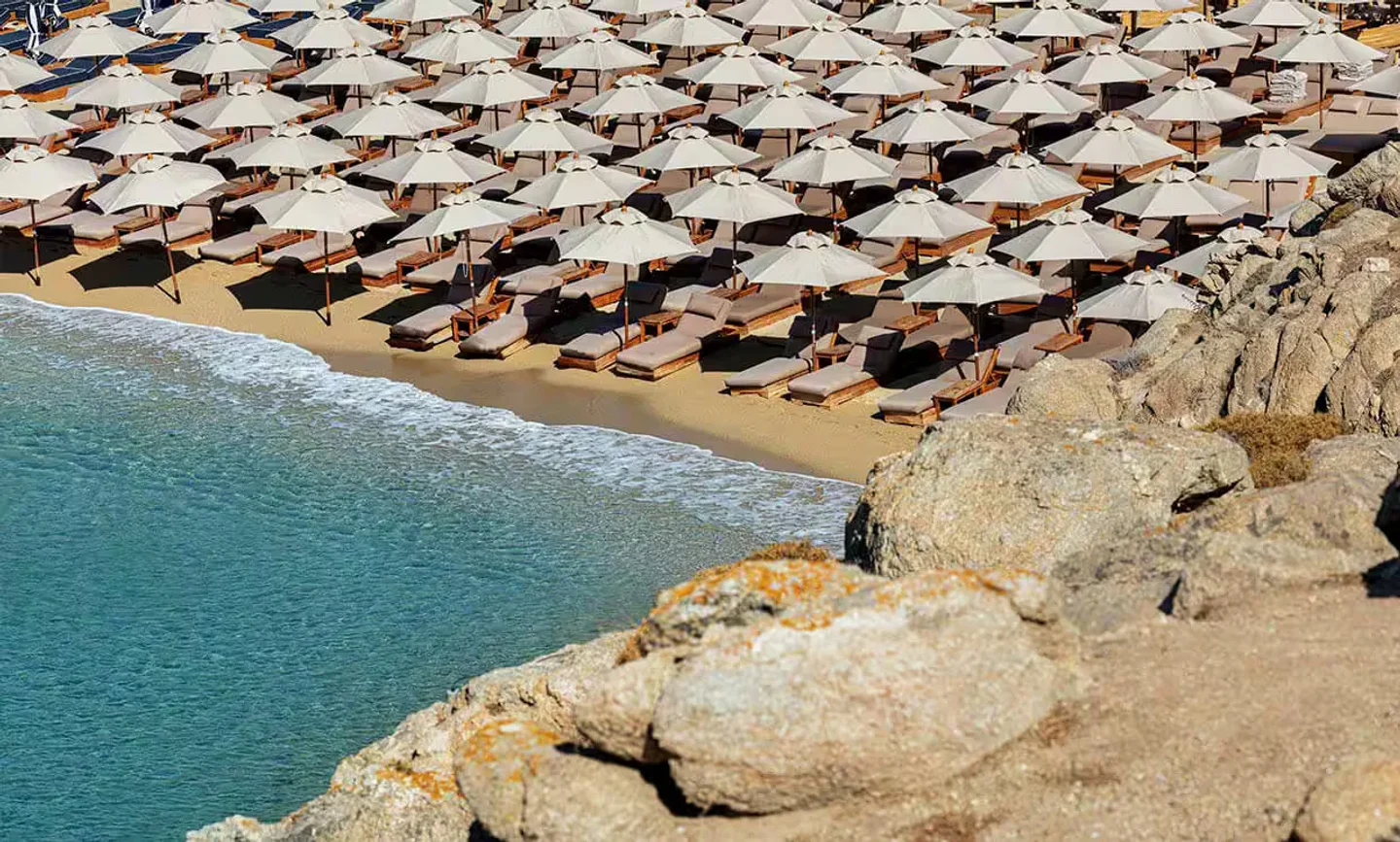 Super Paradise beach club in Mykonos with rows of sunbeds and umbrellas by the turquoise sea