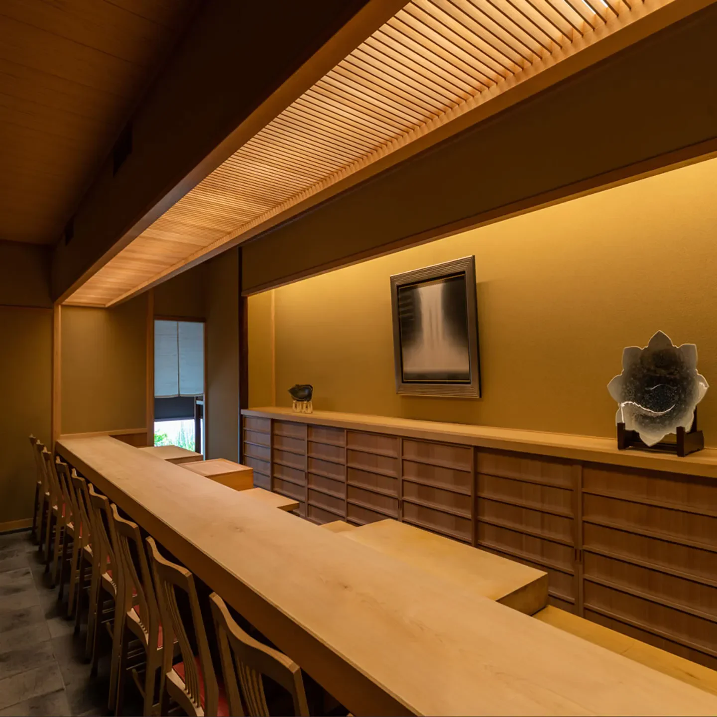Interior of Sushi Harasho in Osaka, showcasing elegant wooden counter and decor.