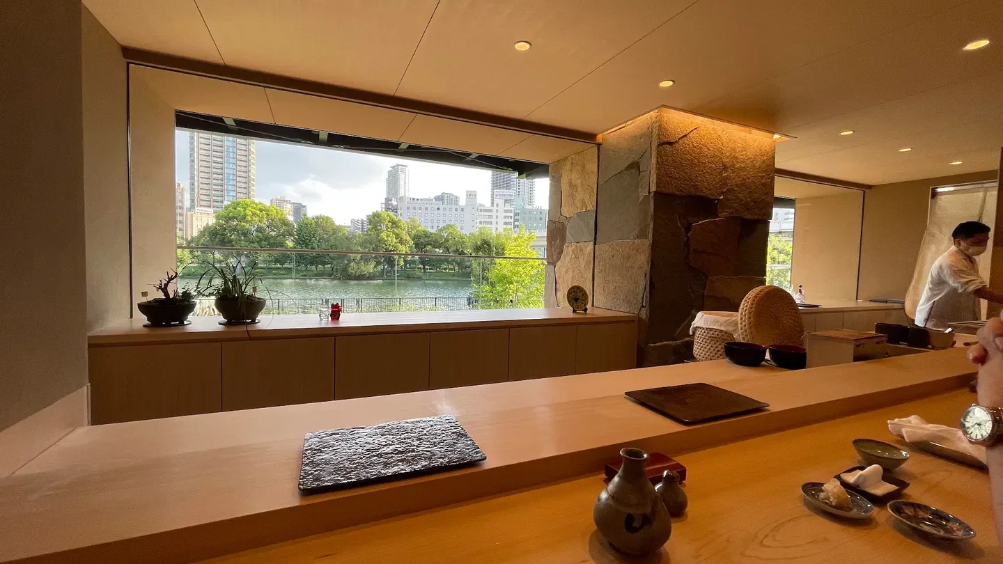 Interior of Sushi Hoshiyama restaurant in Osaka with a view of the city and water.