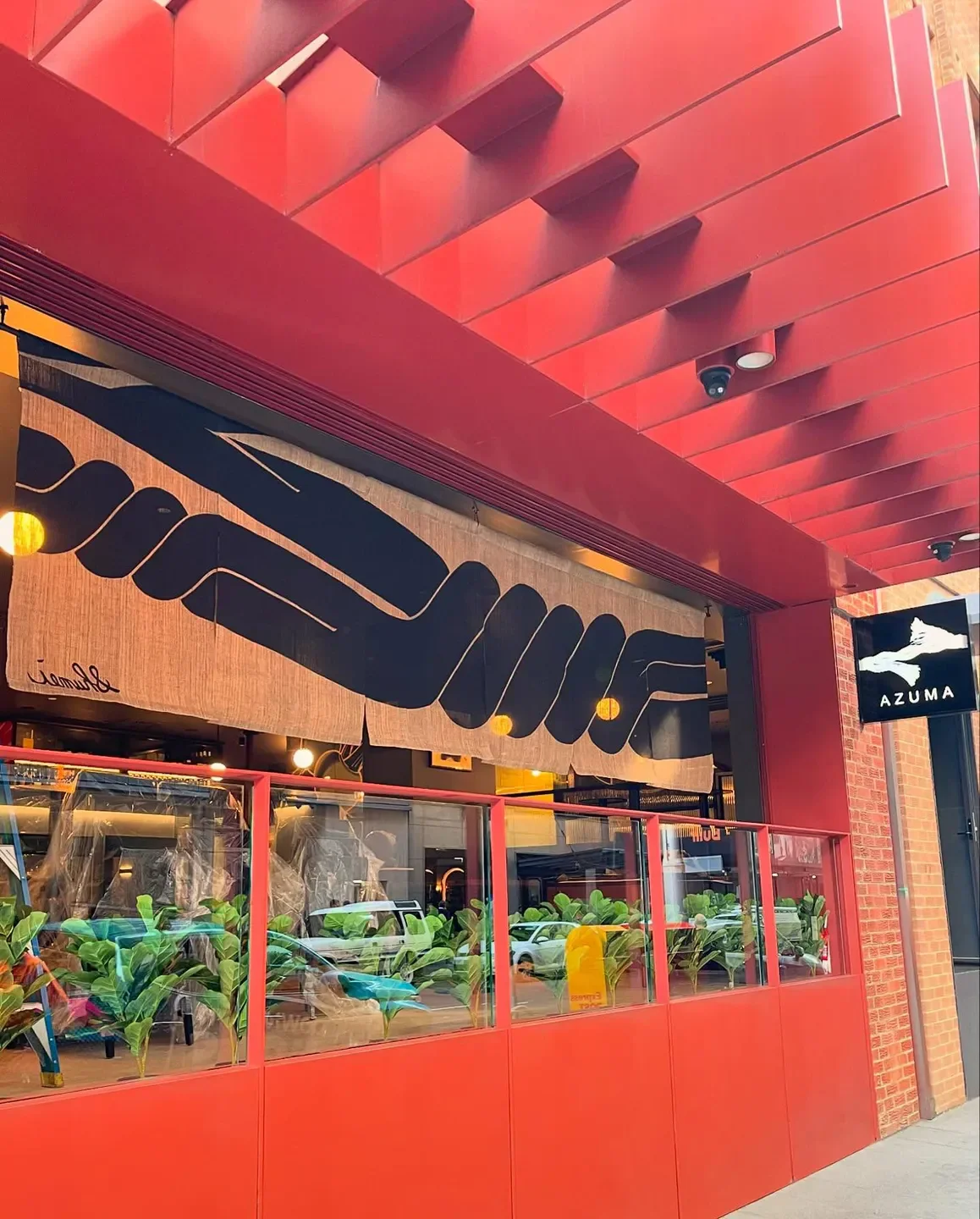 Exterior view of Sushi Kawashima restaurant in Nara, featuring red design and entrance.