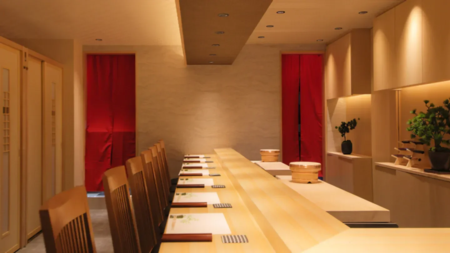 Interior of Sushi Matsumoto in Kyoto, with wooden counter and red curtains.