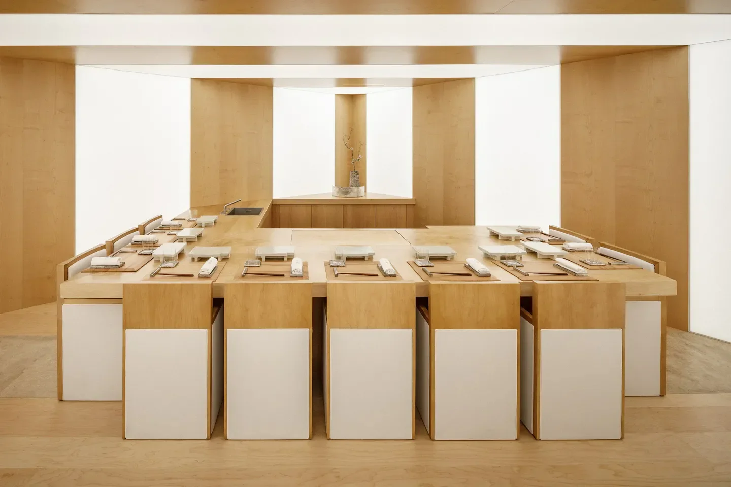 Minimalist interior of Sushi Yoshinaga in Paris, featuring a wooden counter and dining setup.