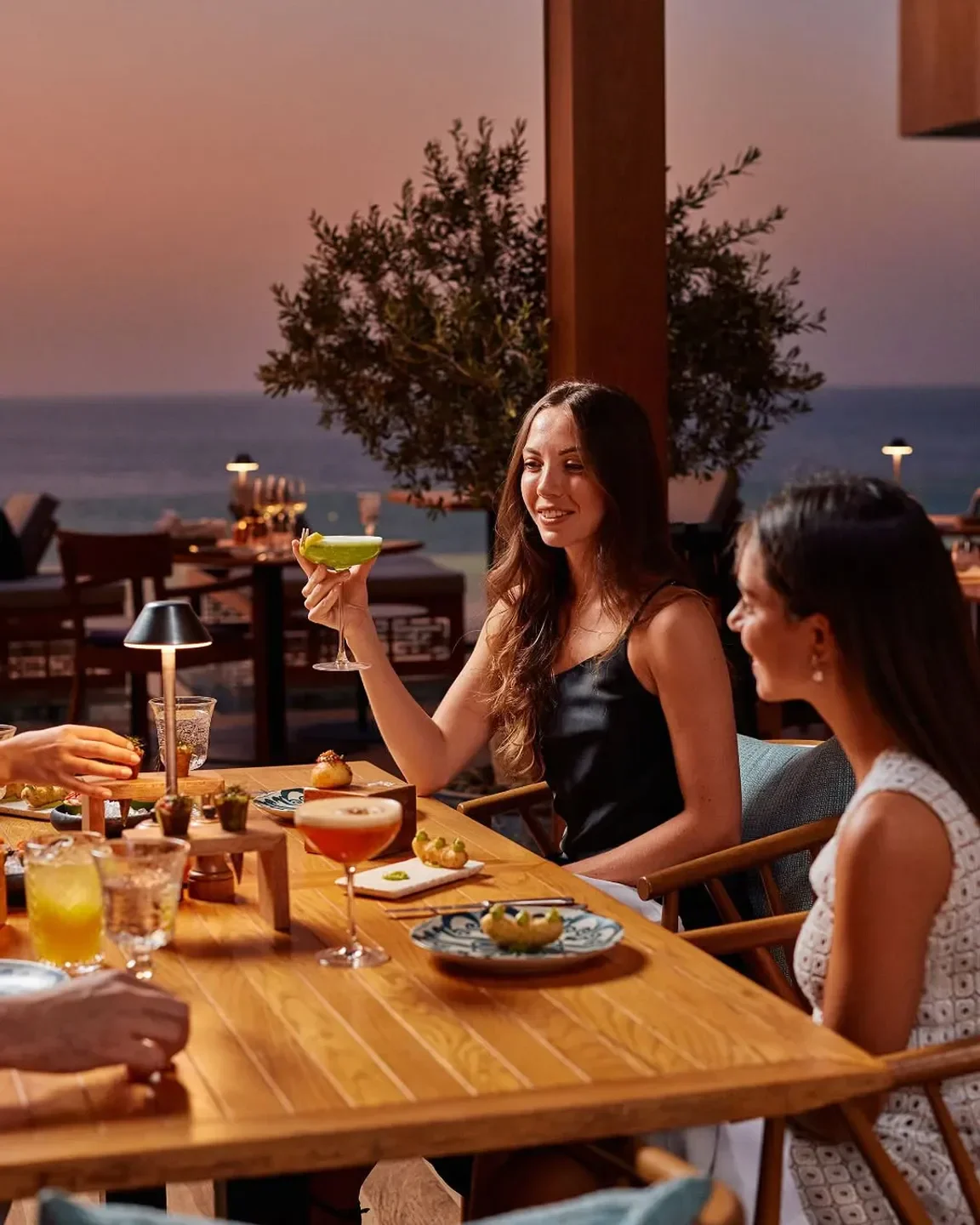 Enjoying cocktails at Tabu Dubai's stylish restaurant with a beautiful sunset view.