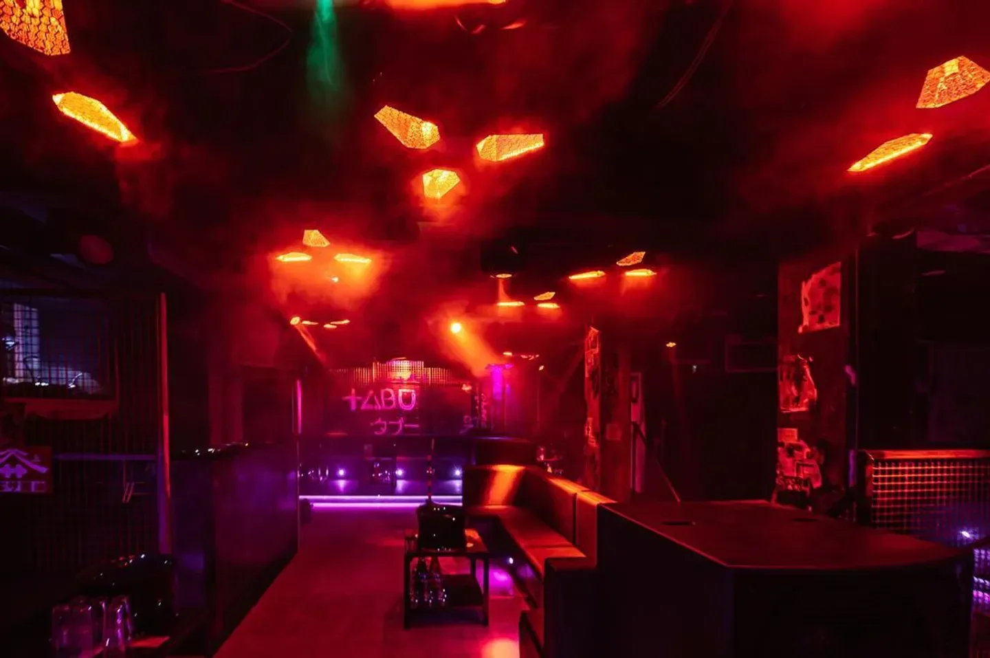 Inside Tabu London nightclub with red lighting and neon accents, a cool atmosphere.