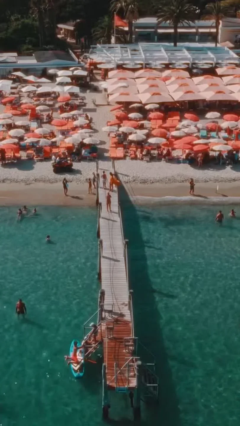 Aerial view of Tahiti Beach restaurant in Saint-Tropez with a pier and umbrellas lining the sandy shore