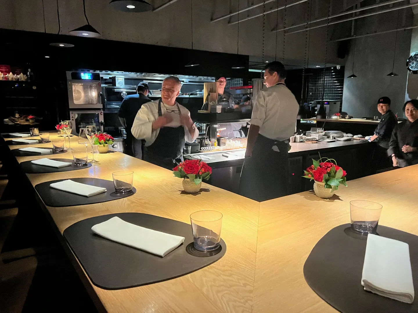 Interior of Taian Table - Shanghai, showing chefs and bar seating in a stylish restaurant.
