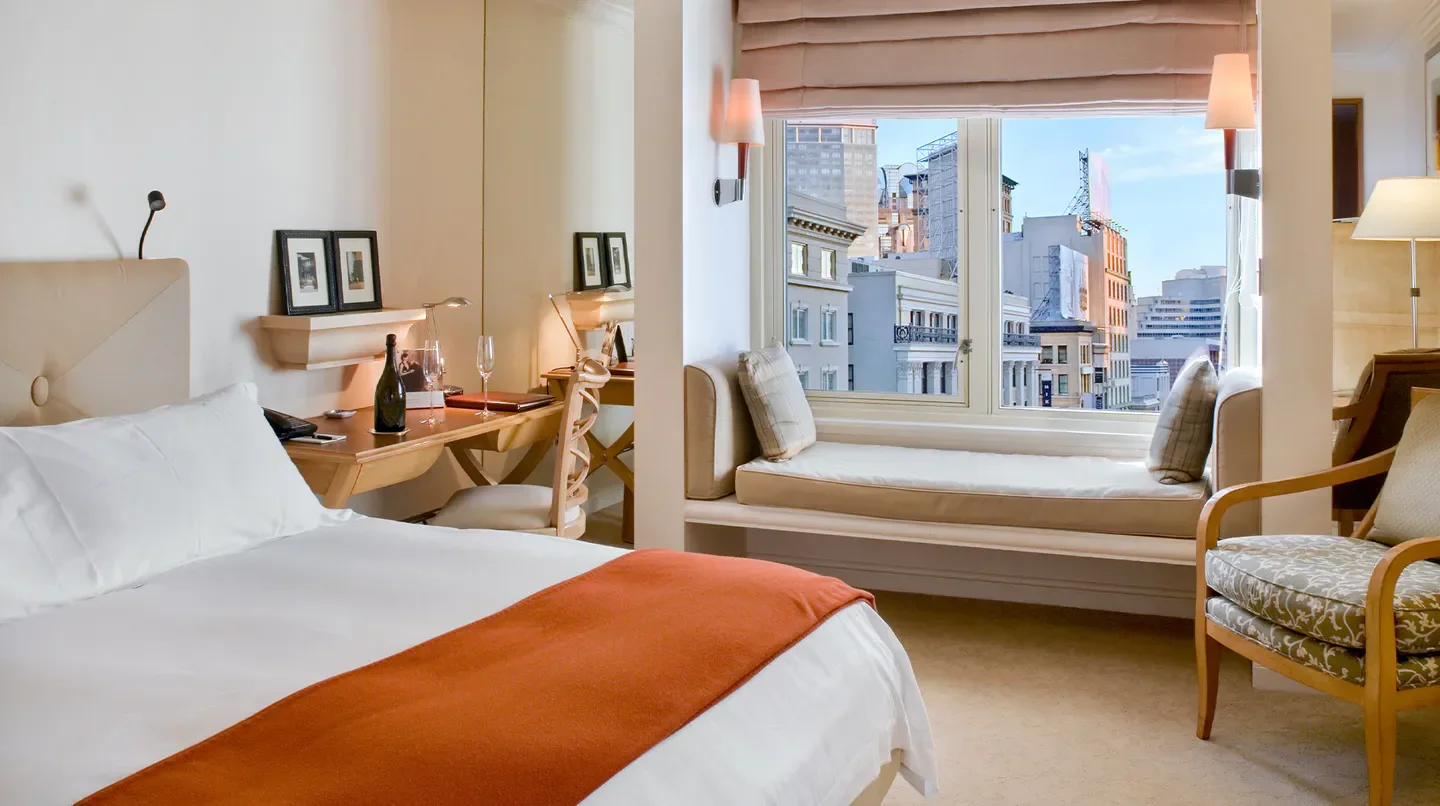 Cozy bedroom at Taj Campton Place in San Francisco, with city views from the window.