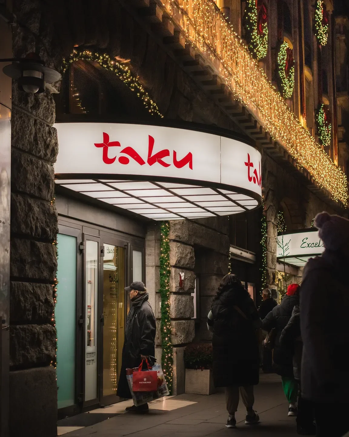 Entrance to taku restaurant in Cologne, illuminated at night with festive decorations.