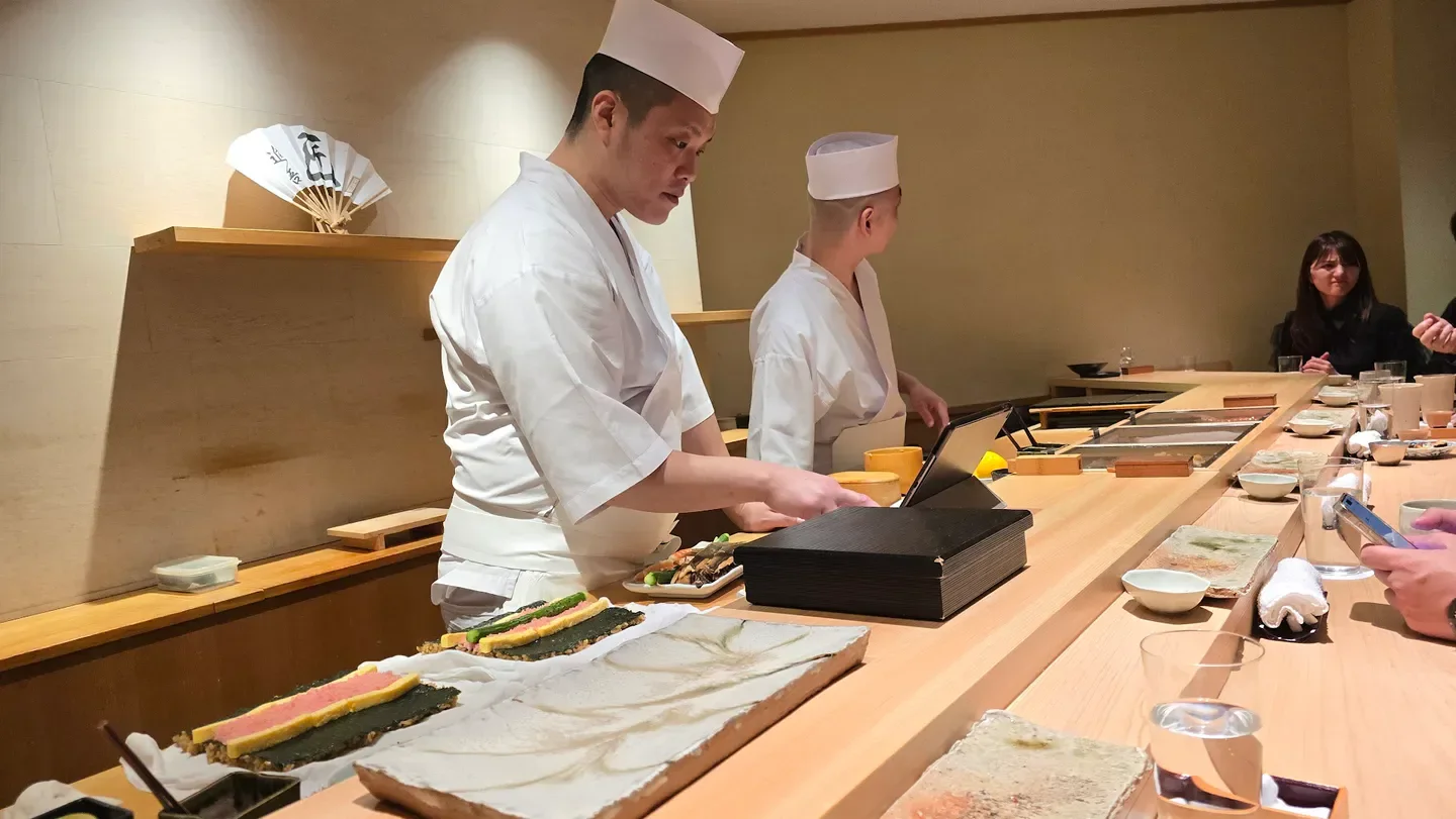 Chefs at work inside Takumi Shingo, a restaurant in Tokyo, preparing sushi for diners.