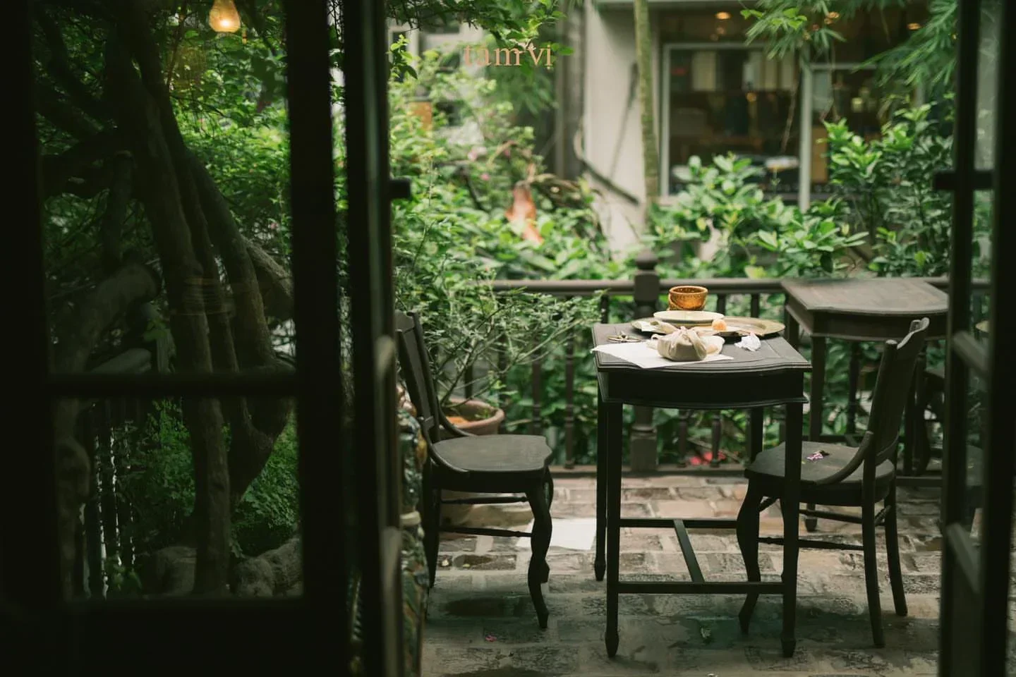 Cozy outdoor dining at Tầm Vị restaurant in Hanoi, showcasing a relaxing, green atmosphere.