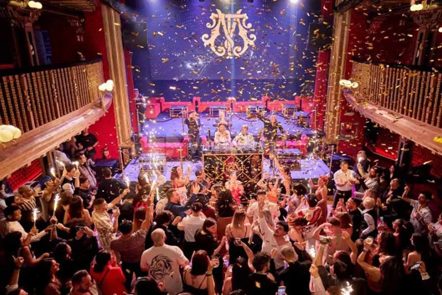 Energetic crowd celebrating at Teatro Magno nightclub in Madrid with confetti and sparks.