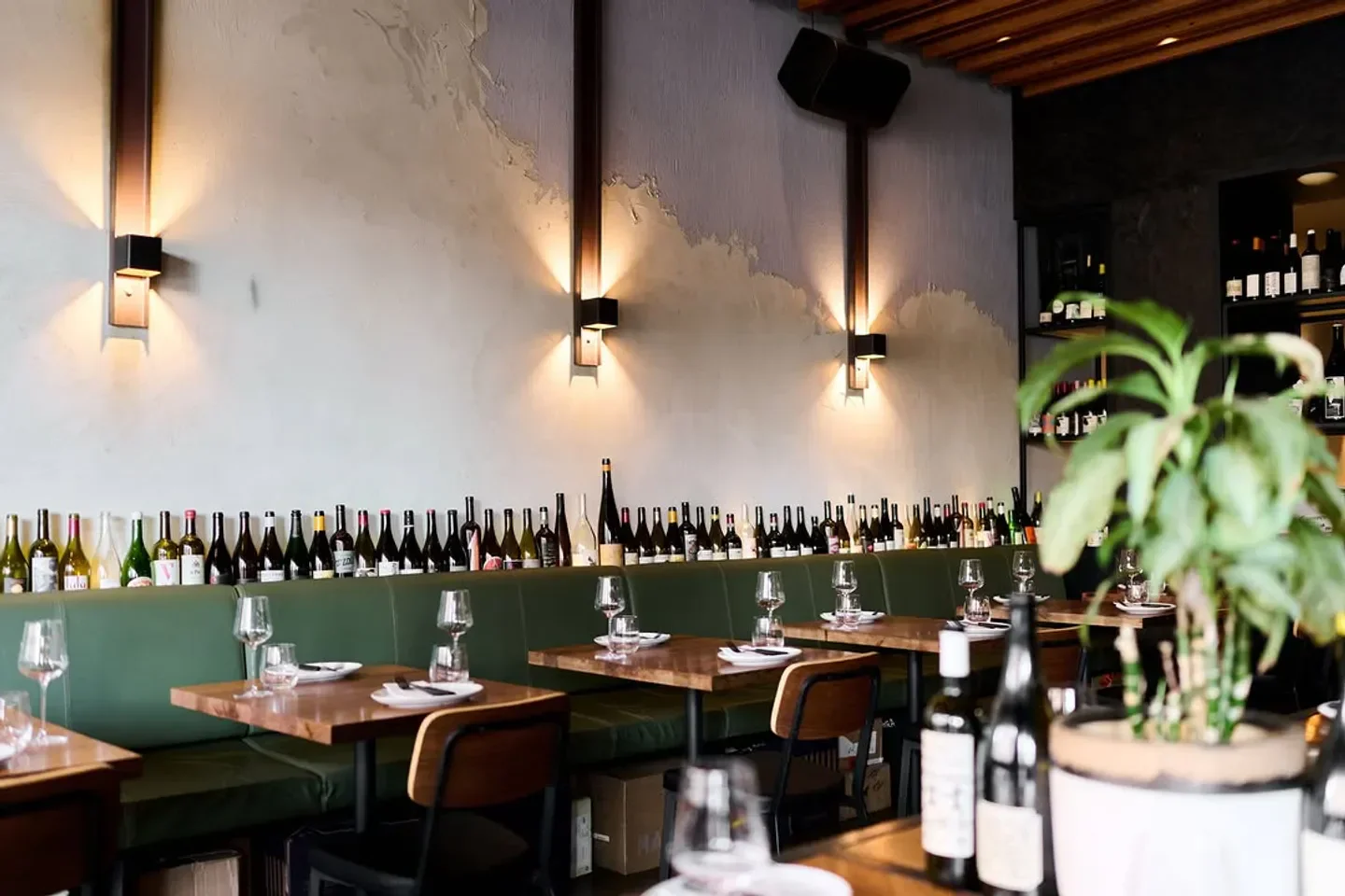 Interior of TERRA restaurant in Canberra, showcasing wine bottles and dining tables.