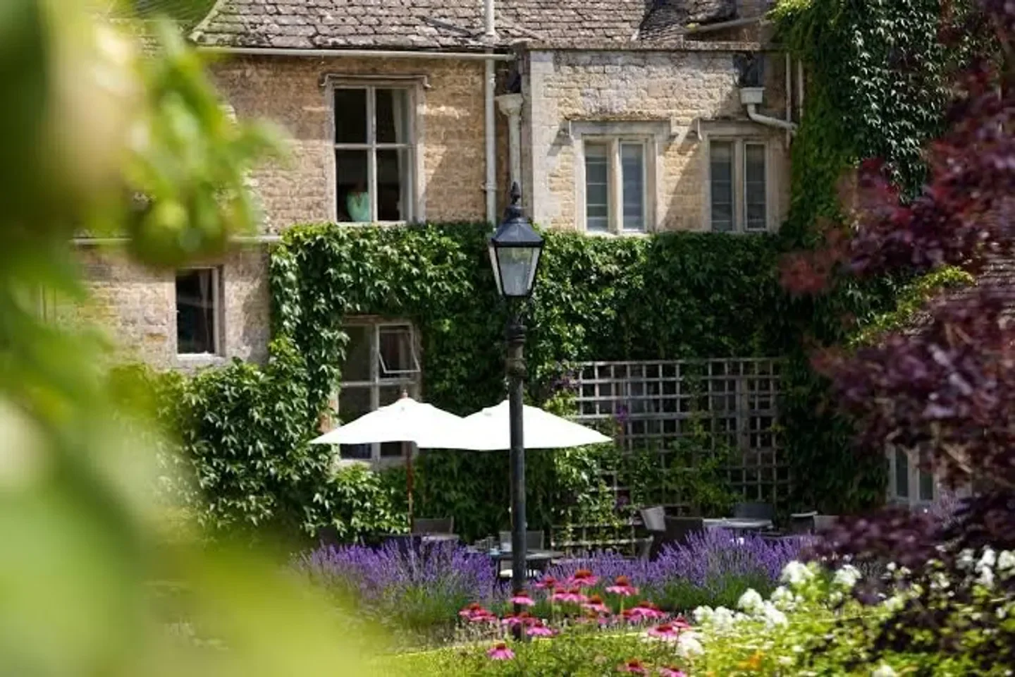 The Atrium restaurant in Cotswolds, outdoor dining space with parasols and blooming flowers