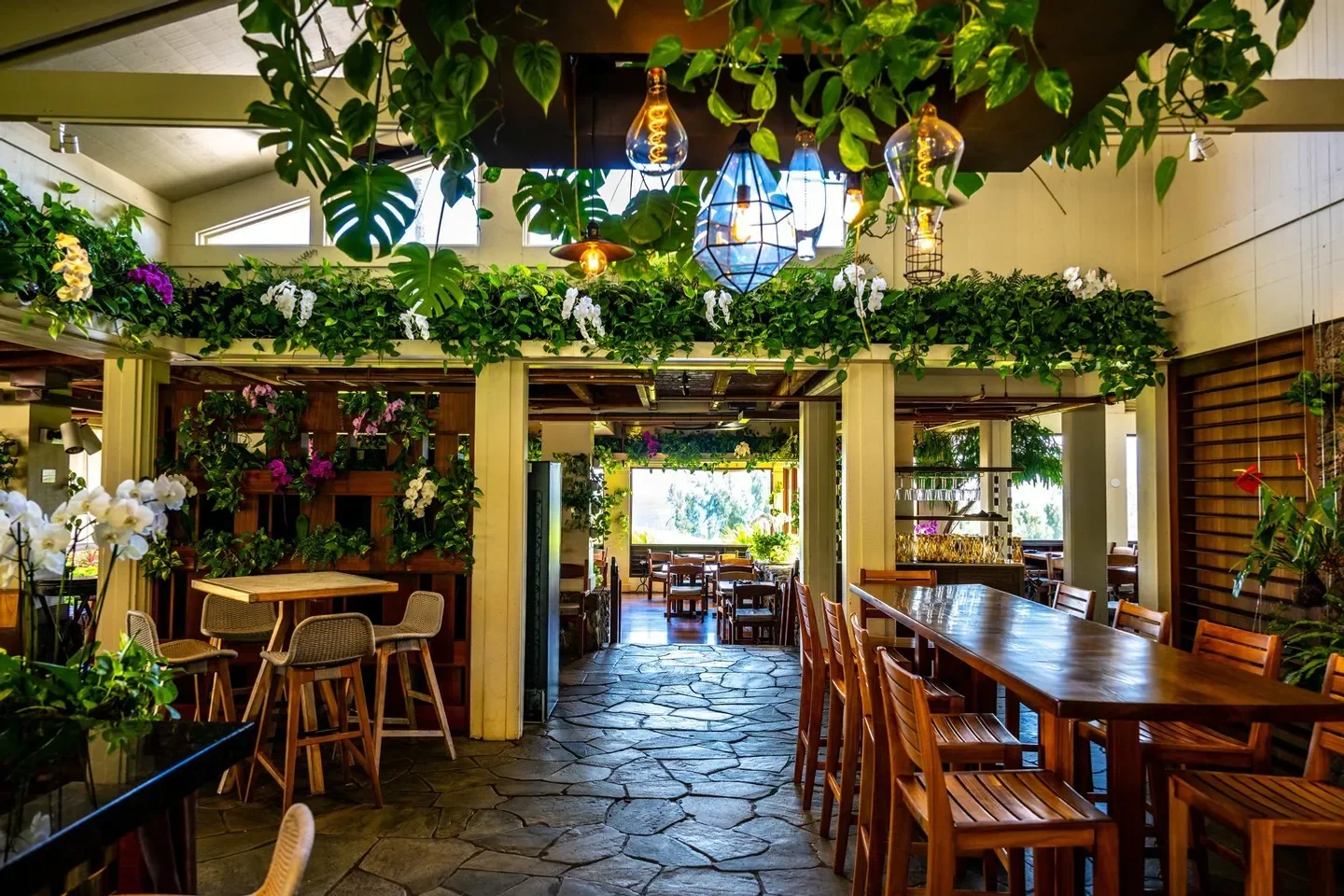 Interior of The Banyan Tree restaurant in Maui, with lush greenery and hanging lights.