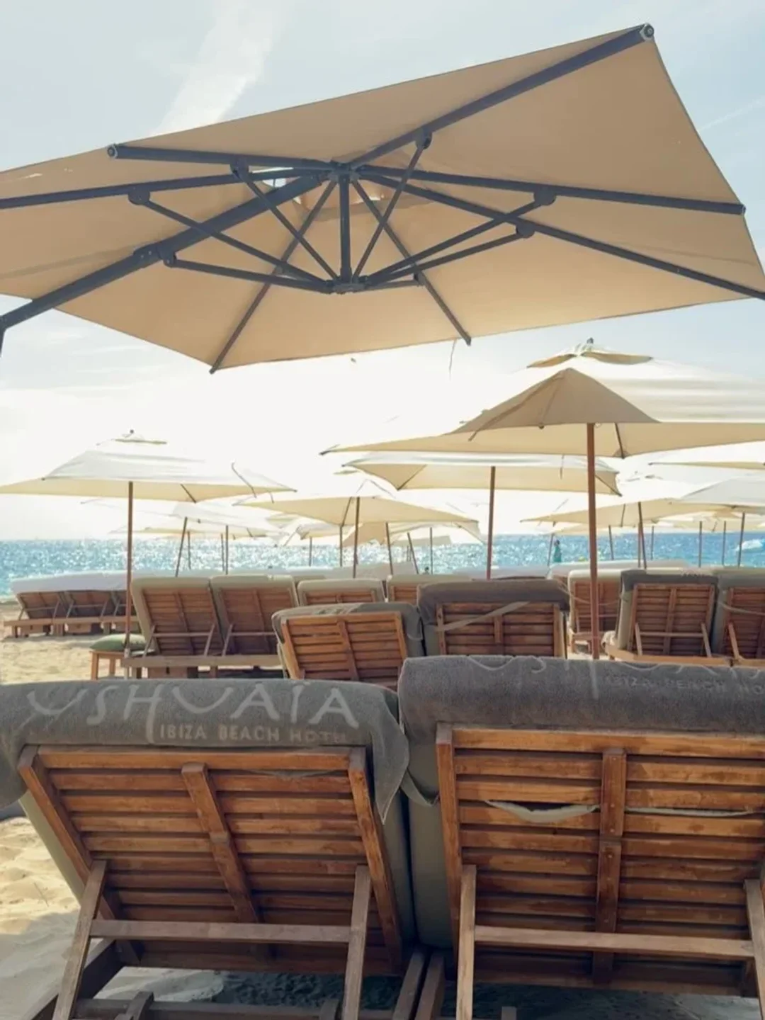 The Beach, Unexpected Ibiza offers lounge chairs and umbrellas on a sandy beach by the ocean.