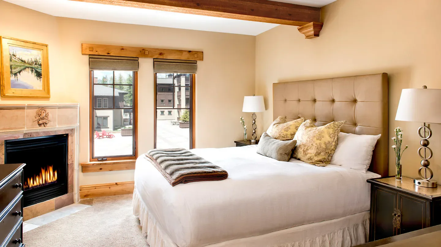 Cozy bedroom at The Chateaux Deer Valley in Park City featuring a fireplace and large windows.