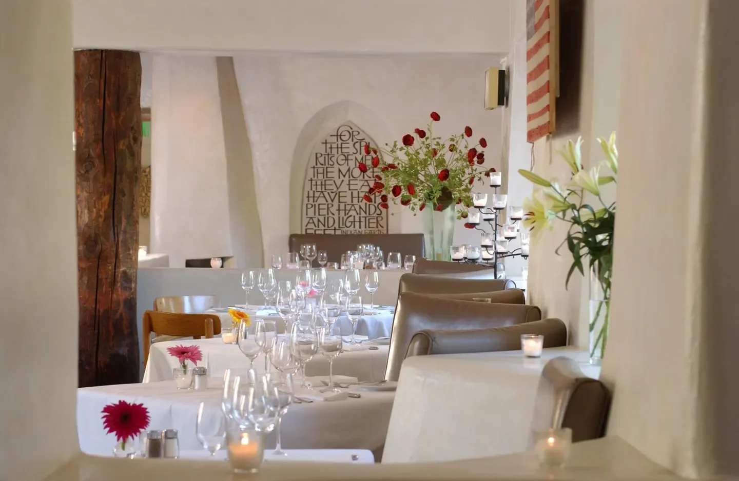 Elegant dining room at The Compound Restaurant in Santa Fe, with flowers and candles.