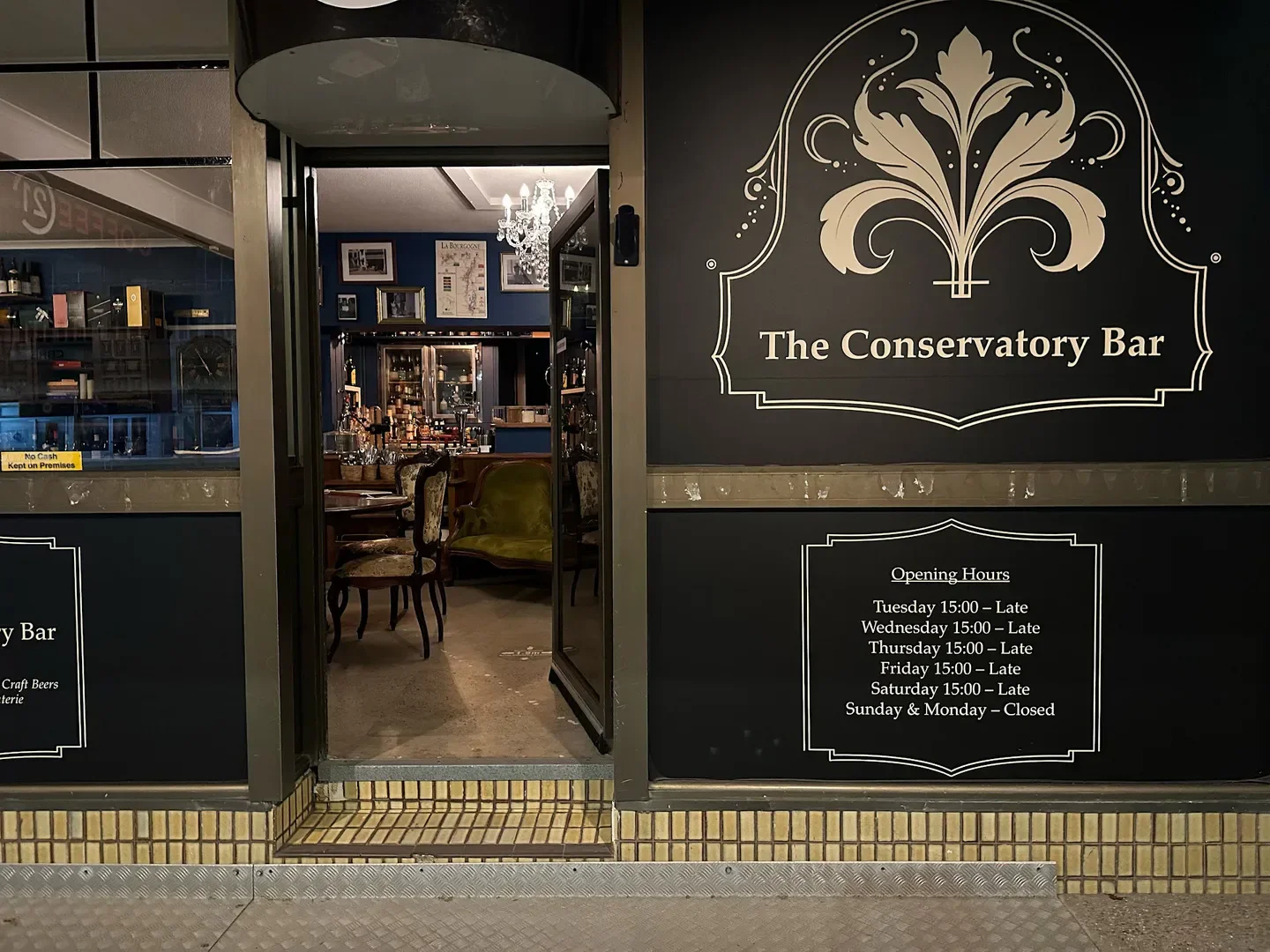 Entrance to The Conservatory Bar in Cairns, showing opening hours and interior view.