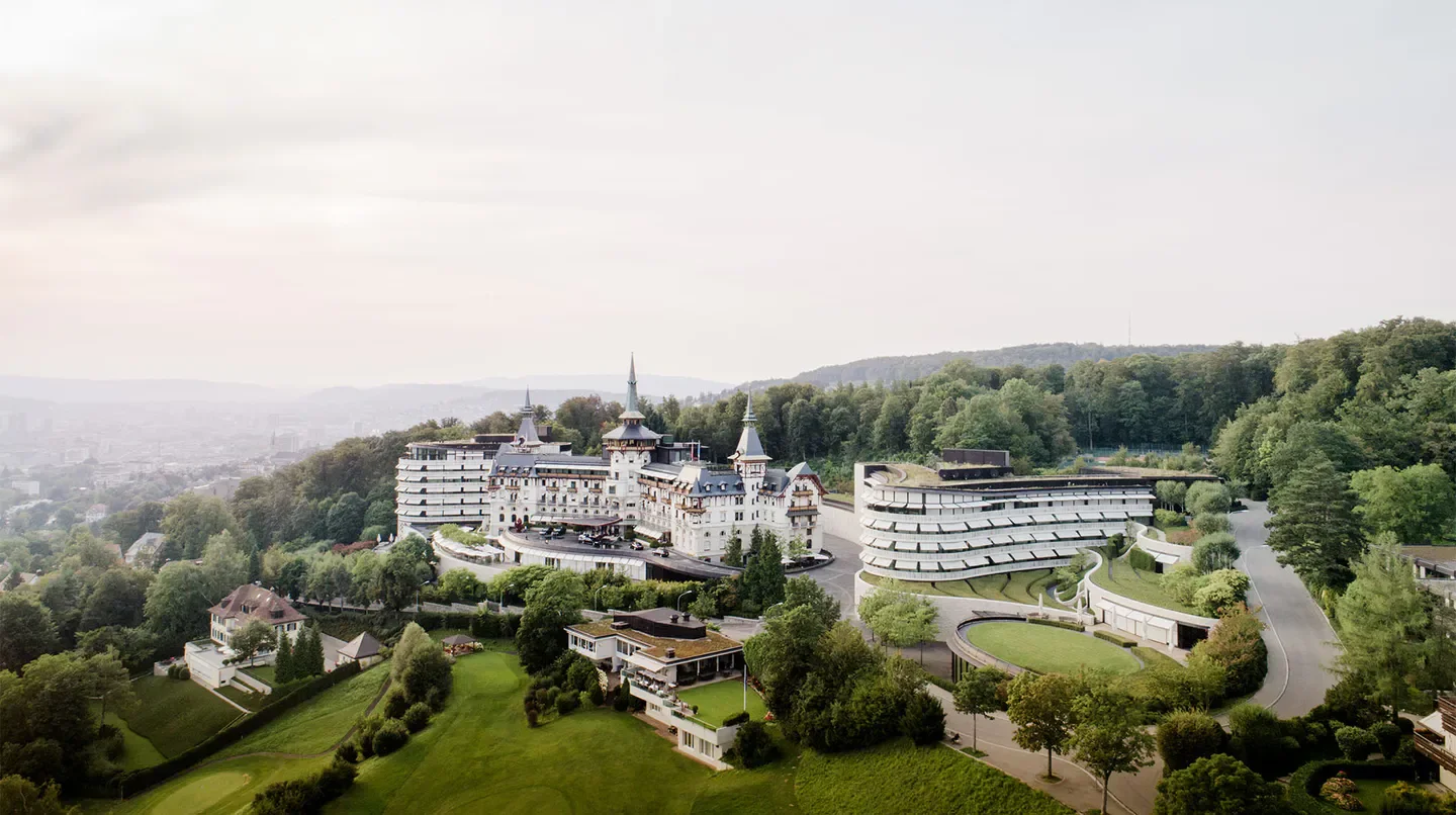 Aerial view of The Dolder Grand hotel in Zurich, surrounded by lush greenery