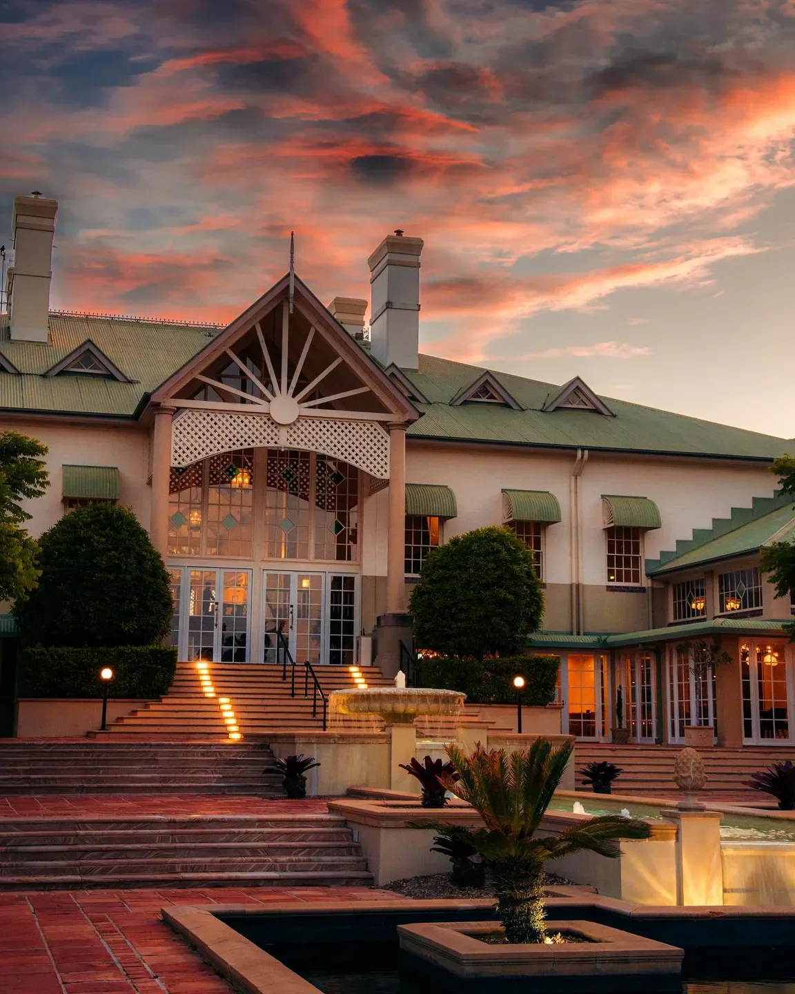 Exterior of The Fireplace Restaurant in Gold Coast at sunset, with fountain and steps.