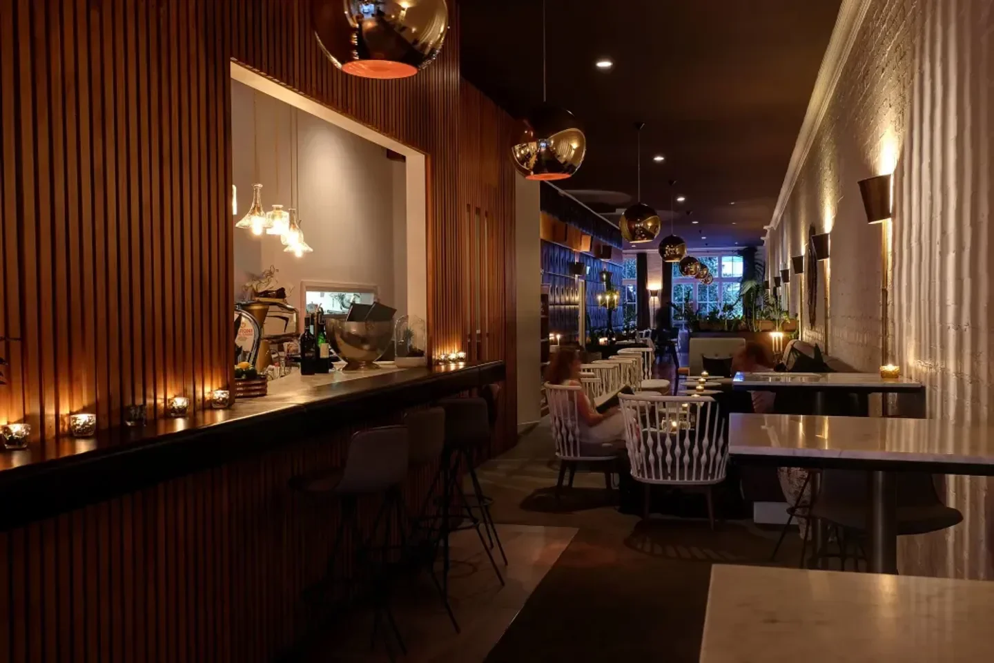 Interior of The Grove restaurant in Auckland, with a long bar and cozy lighting