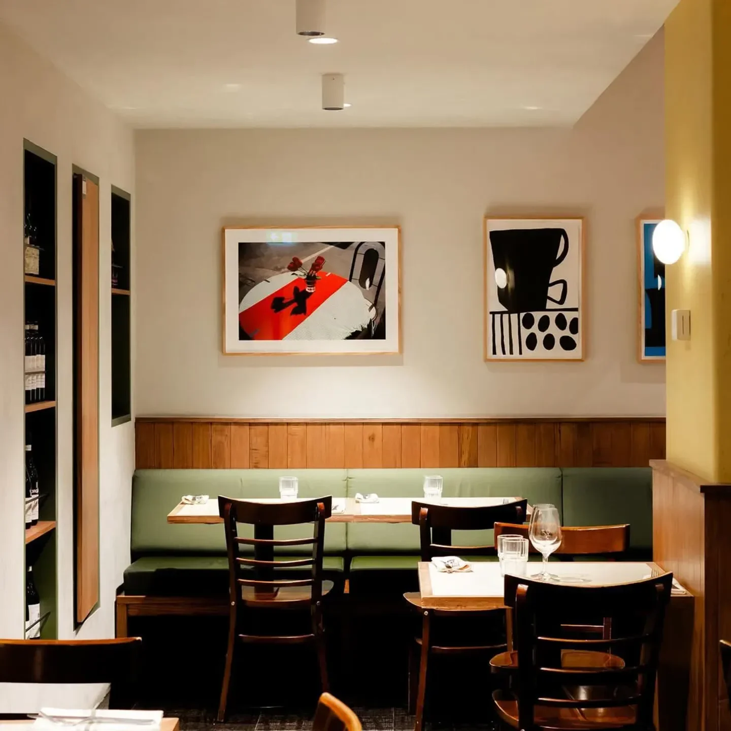 Cozy dining area inside The Hardware Club restaurant in Melbourne, with art and wooden tables.
