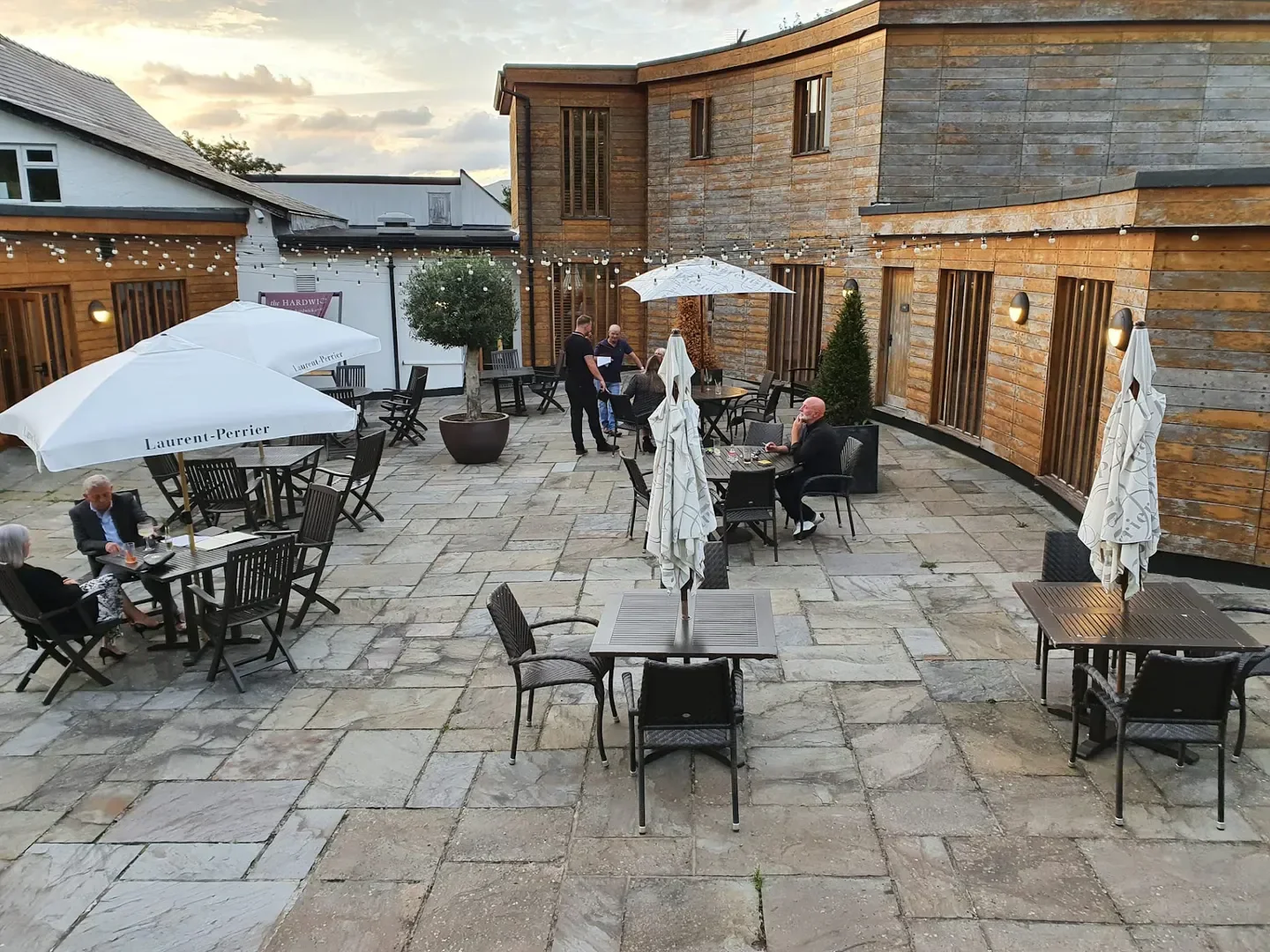 Outdoor dining at The Hardwick restaurant in Wales, featuring umbrellas and seating.