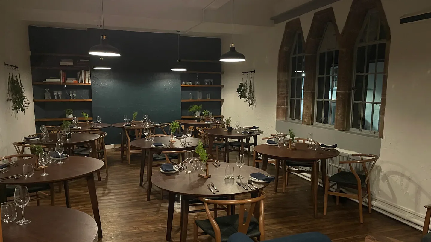 Interior dining space at The Jackdaw restaurant in Wales with round tables.