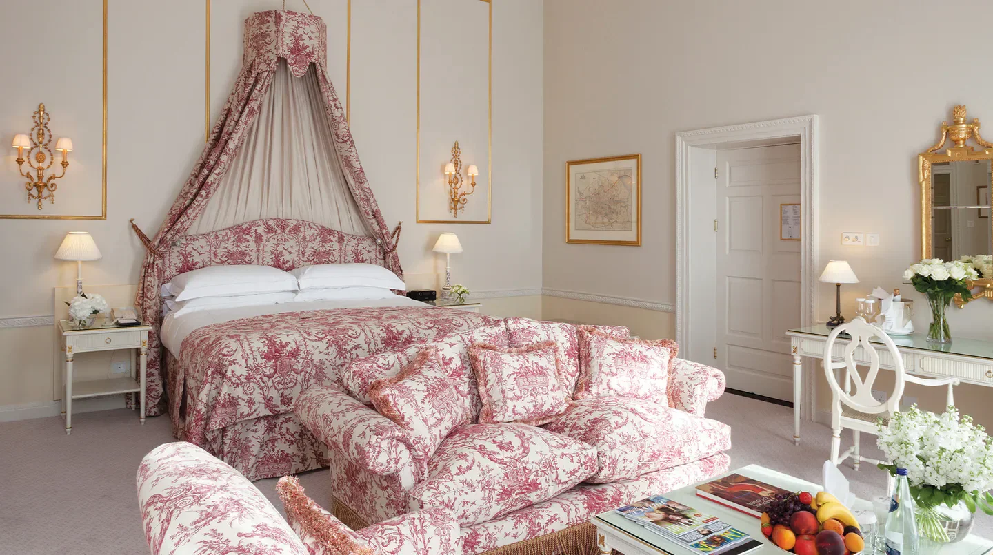 Elegant bedroom at The Merrion Hotel in Dublin, featuring a canopy bed and sofa.