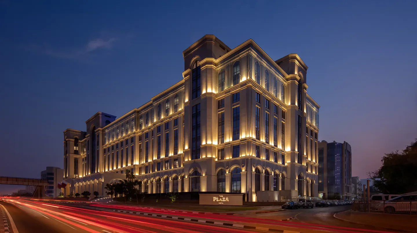 The Plaza Doha, LXR Hotels & Resorts, illuminated at dusk in Doha with traffic streaks.