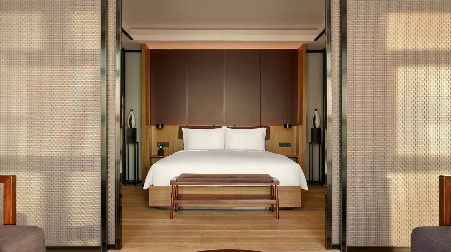 Elegant bedroom at The PuXuan Hotel and Spa, Beijing with natural light and wood accents.