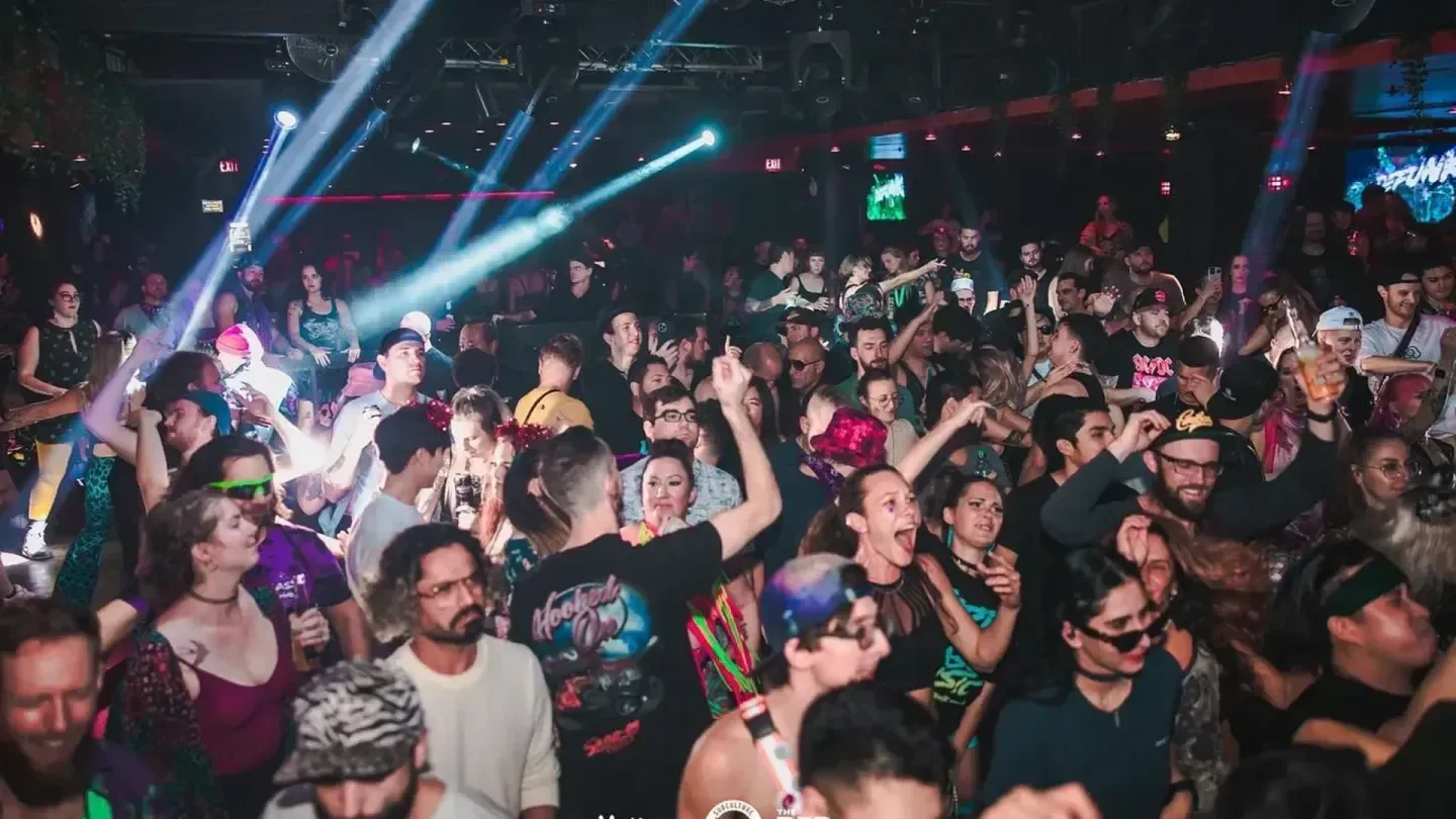 Energetic crowd dancing inside The Red Room nightclub in Vancouver with laser lights.