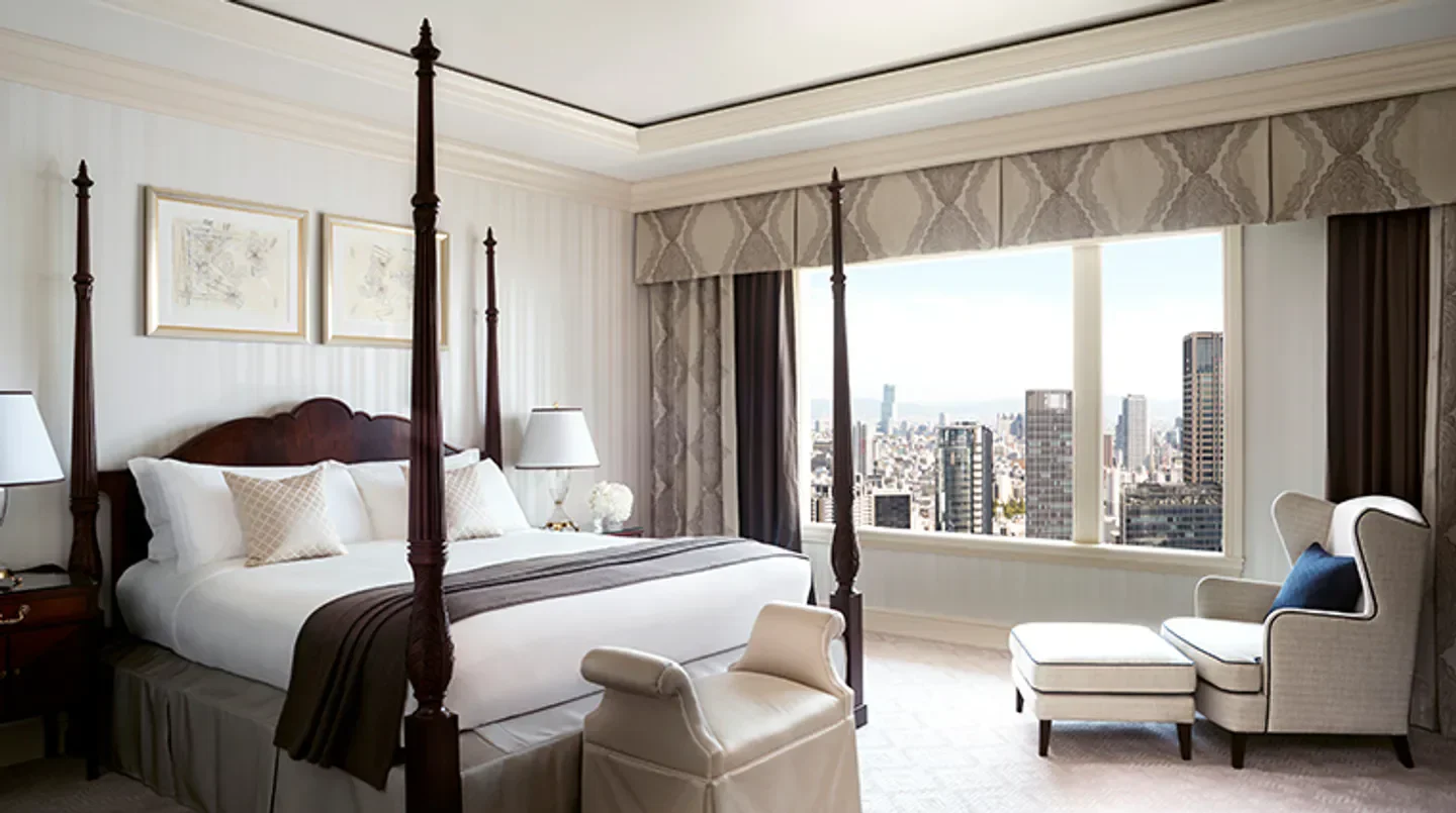 Elegant bedroom at The Ritz-Carlton, Osaka, with city views of Osaka from large windows.