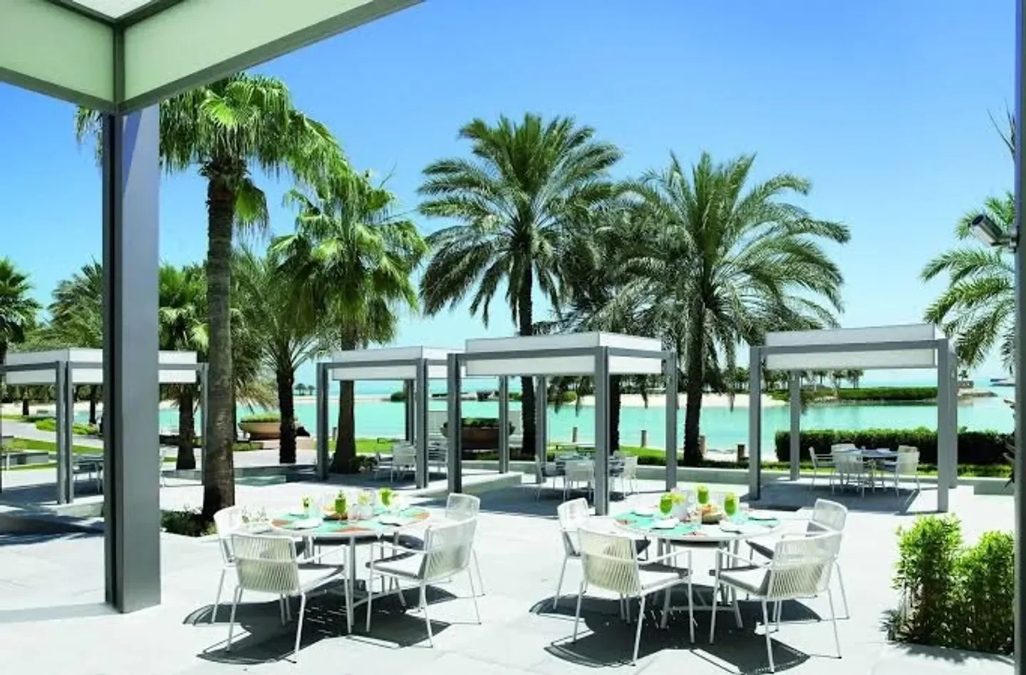 Outdoor dining at The Ritz-Carlton Spa, Bahrain in Manama, surrounded by palm trees and water views
