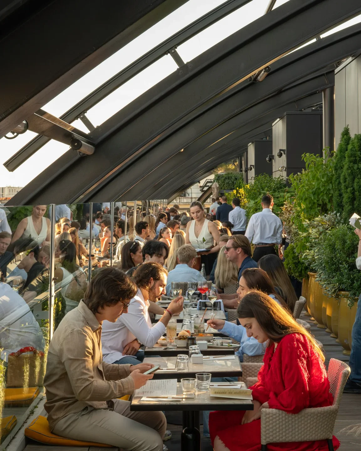 Diners enjoy a lively atmosphere at The Roof, a chic rooftop restaurant in Paris with stylish seating.