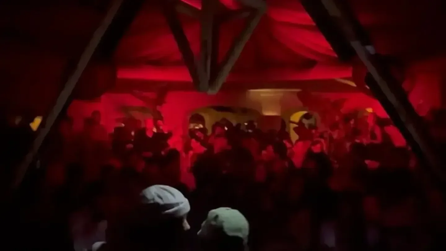 Energetic crowd at The Sanctuary nightclub in Porto Cervo, Italy, with red lighting.