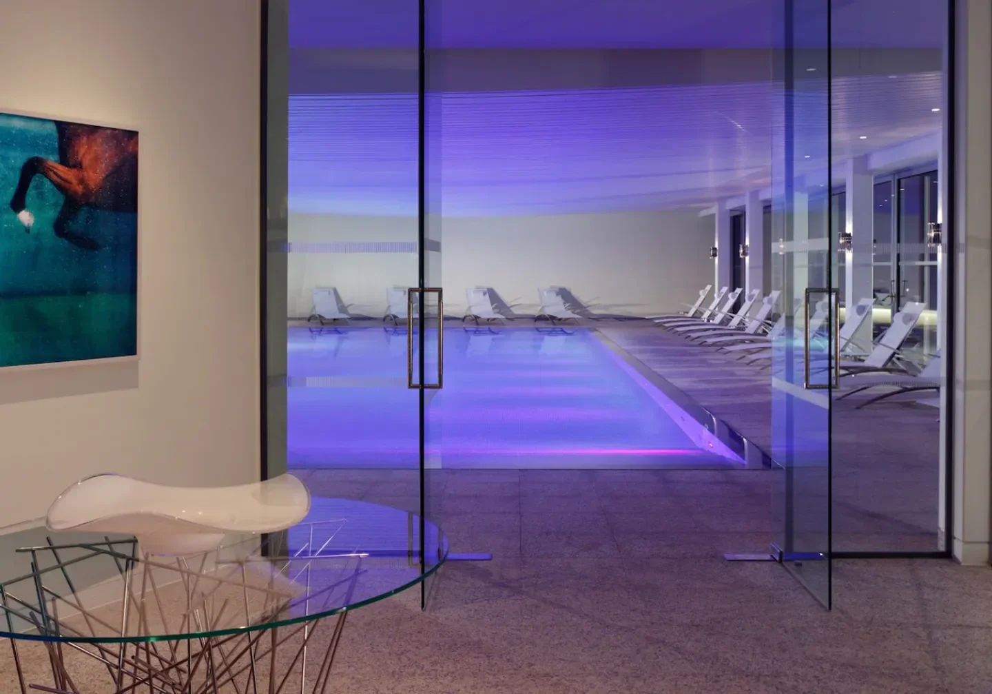 The Spa at Coworth Park, London, features a pool with loungers and stunning purple light.