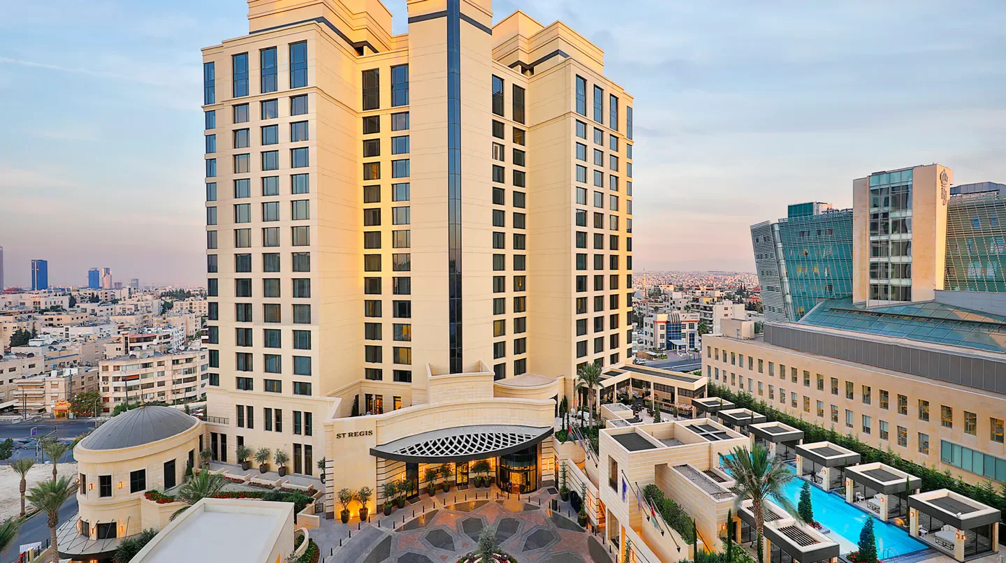 Exterior of The St. Regis Amman hotel in Amman, featuring a pool and city views.