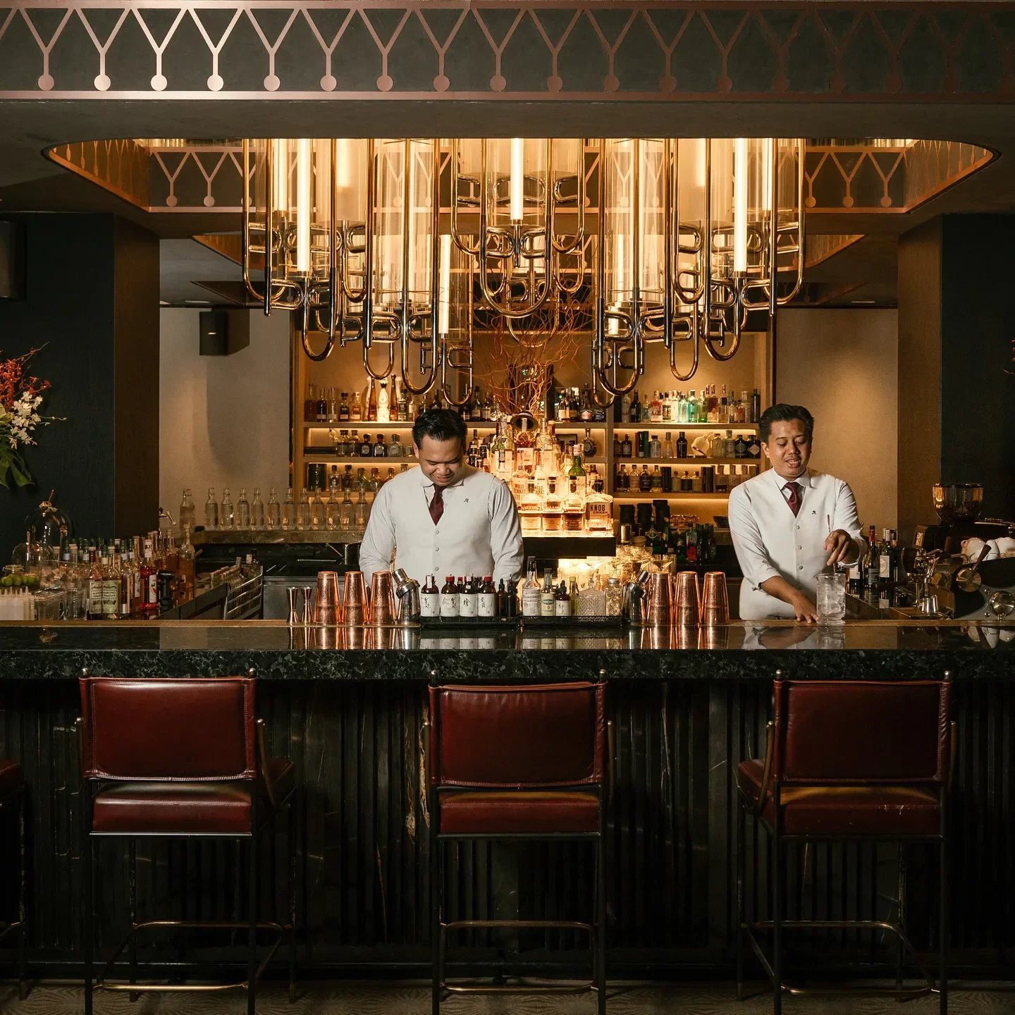 Stylish interior of The St. Regis Bar (Jakarta), with bartenders in Jakarta preparing drinks.