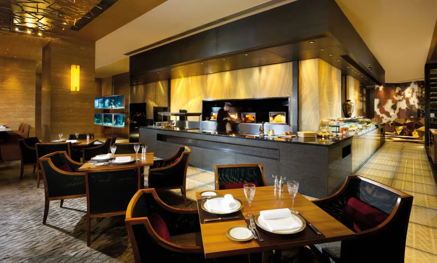 Interior of The St. Regis Bar (Macau) restaurant with tables and kitchen view in Macau