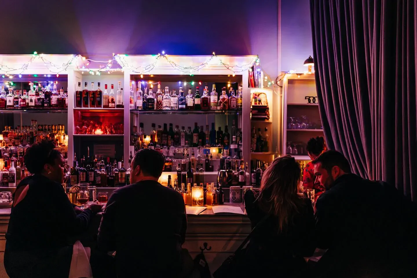 Cozy bar scene at The Violet Hour, Chicago. People at a dimly lit bar enjoying drinks.