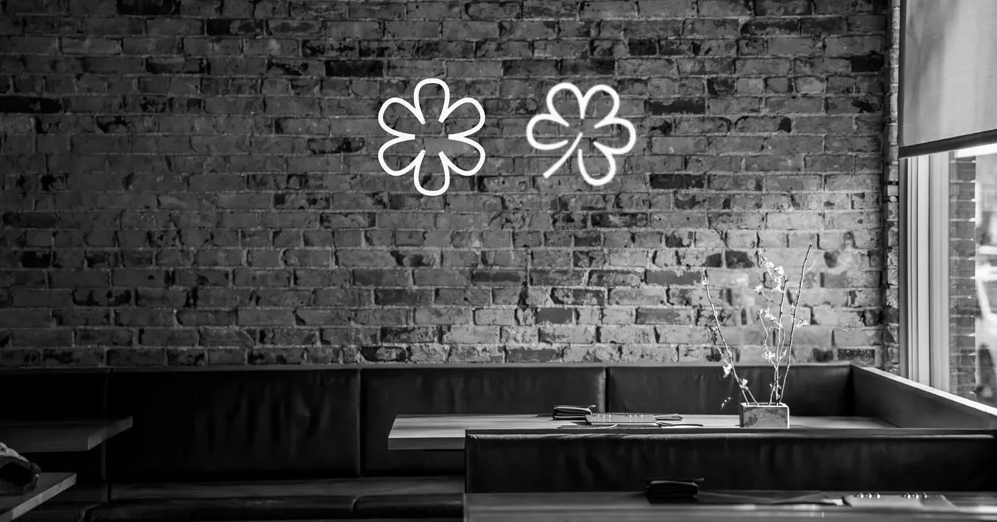 Interior of The Wolf's Tailor in Denver, featuring brick wall and neon flower lights.