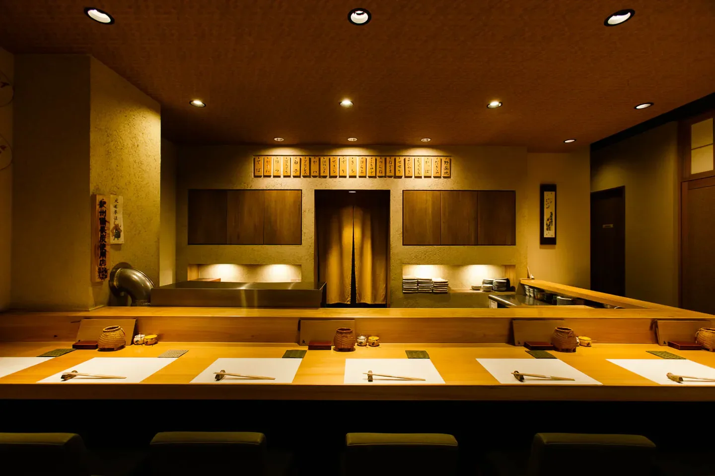 Interior dining space at Torisho Ishii in Osaka, featuring elegant wood and lighting design.