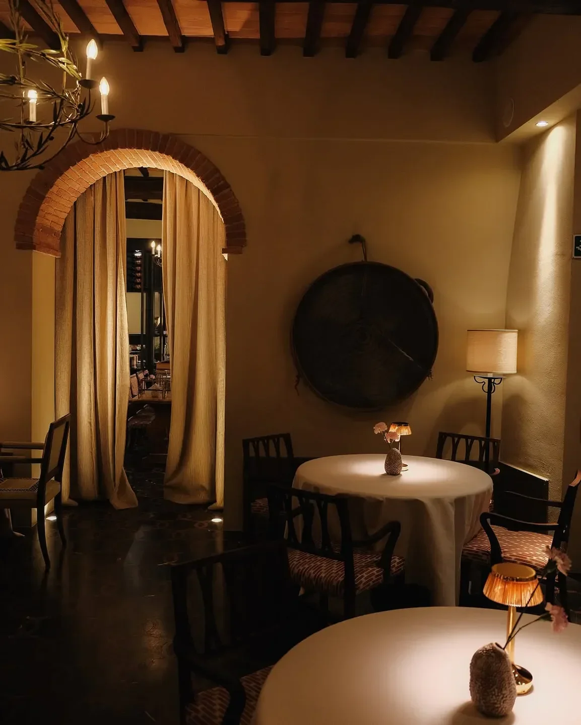 Elegant dining room in Tosca restaurant, Tuscany, with arched doorway and soft lighting.