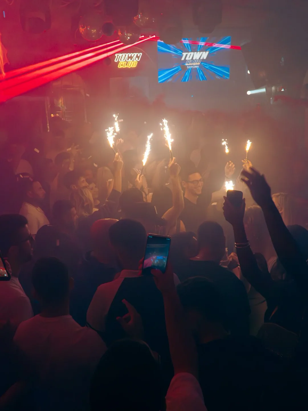 Town Club nightclub ambiance with patrons holding sparklers and red laser lights illuminating the scene.