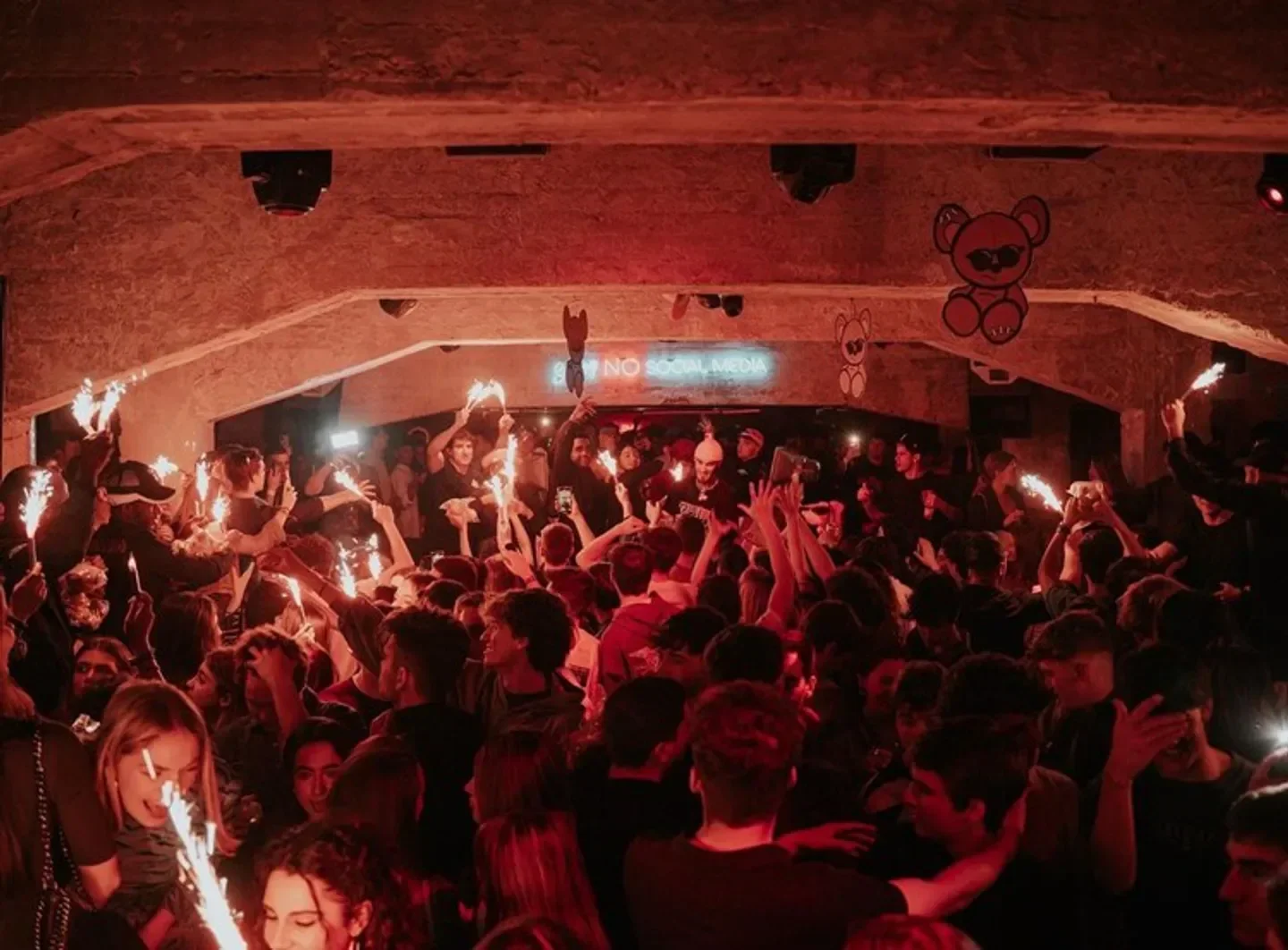 Energetic crowd partying with sparklers at ToyRoom Madrid nightclub, vibrant atmosphere.