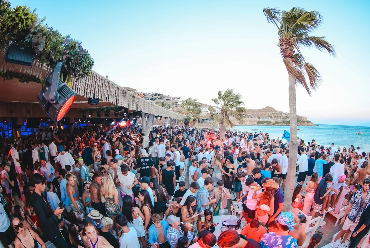 Crowd at Tropicana in Mykonos, a popular beach club and restaurant in Greece, enjoying drinks and music.