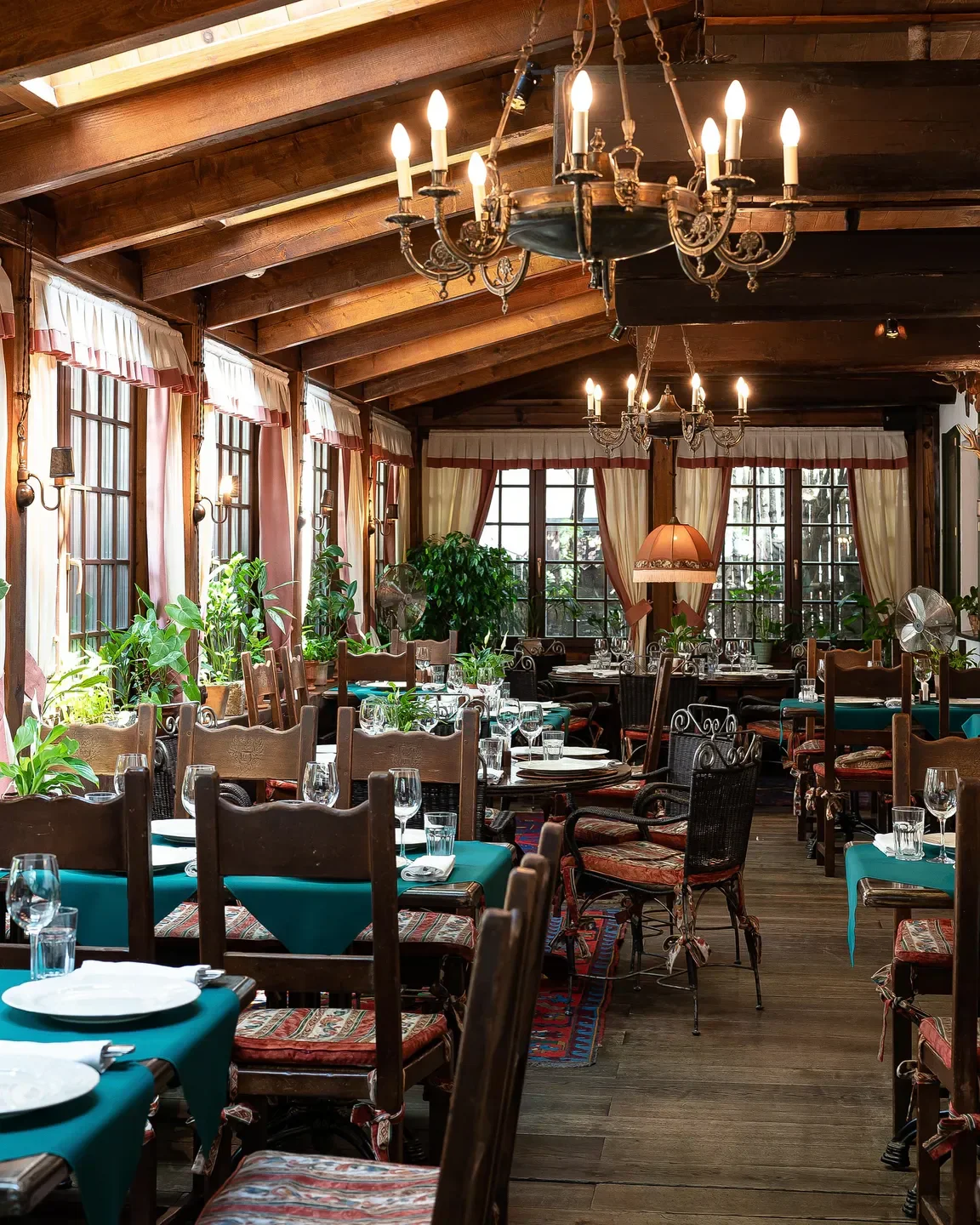 Elegant dining room interior at Tsarskaya Okhota restaurant in Moscow with chandeliers.