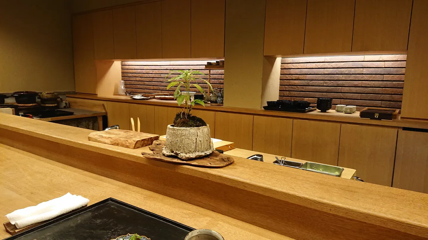 Elegant interior of Tsukumo restaurant in Nara, featuring wooden counter and artistic decor.